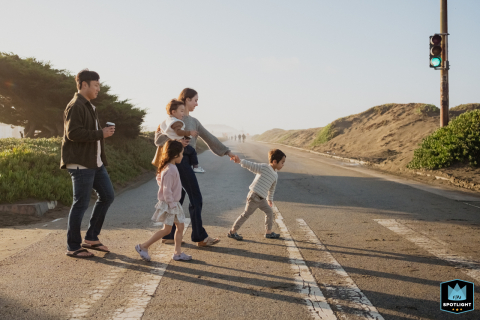 In San Francisco, California, kids eagerly pull their parents across a crosswalk towards the beach, capturing the excitement of a family adventure by the ocean.