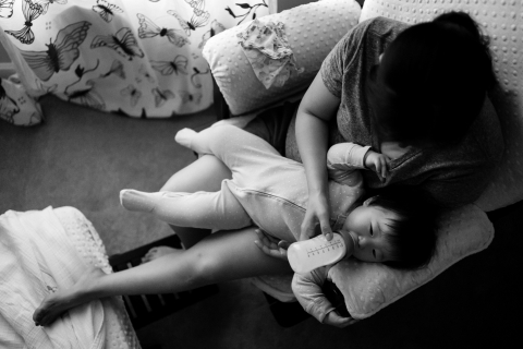 Mother feeds baby daughter a bottle