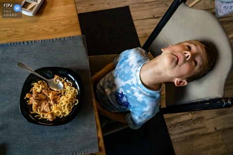 Familiefotografie in Düsseldorf van een jongen die aan de eettafel valt