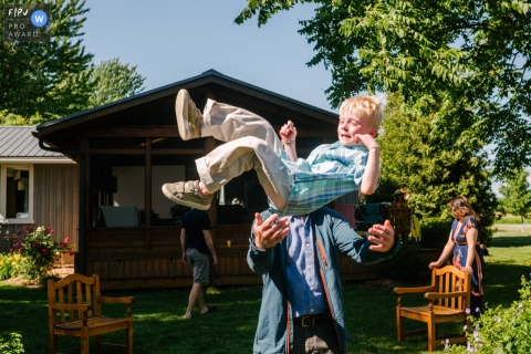 Photographie de famille documentaire de Kingston, en Ontario, montrant un grand-père jetant son petit-fils en l'air