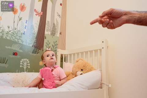 A Ribeirao Preto, Sao Paulo family photographer documented this little girl in bed given directions by dad at the ready