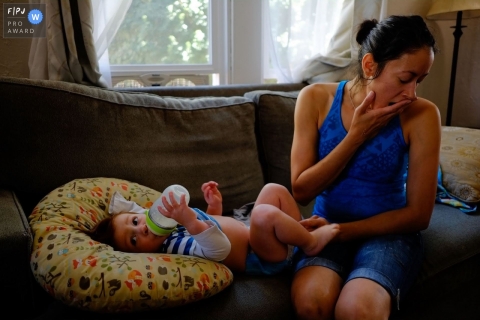 Phoenix, Arizona family photography documenting a Mother yawns as her son drinks from his bottle as they prepare for their day