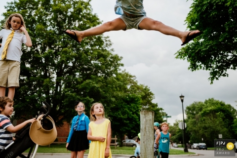 Photographie de famille documentaire de Boston chronique Une fille sautant en l'air pendant que ses cousins ​​regardent