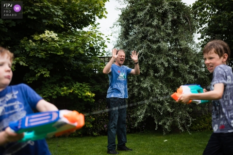 Cambridgeshire, Royaume-Uni photographie de famille documentaire d'un combat familial au pistolet à eau dans le jardin