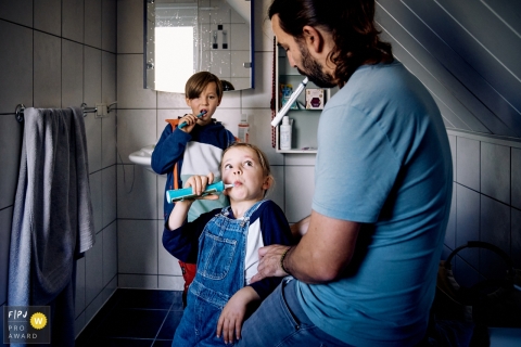 Photographie de famille documentaire de Bonn montrant la routine matinale avec papa dans la salle de bain en train de se brosser les dents