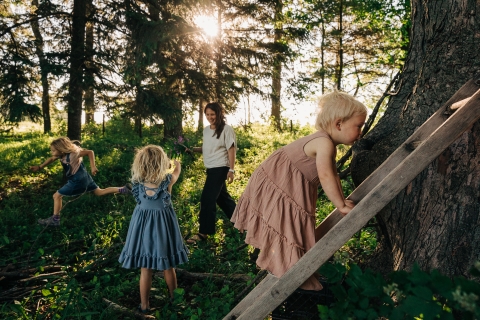 three girls and mother in the woods, sunlight coming through the trees 