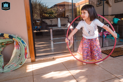 In São Paulo, Brazil, a young girl plays with hula hoops on the porch, bringing a sense of joy and playfulness to the backyard patio setting.
