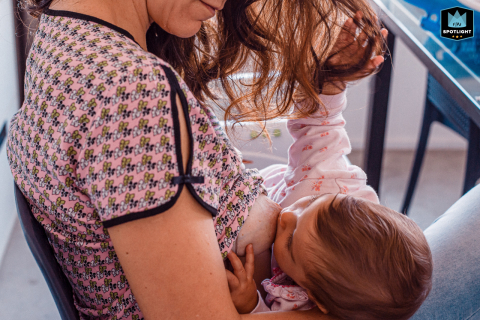 In São Paulo, Brazil, a detailed shot captures a baby nursing while gently playing with mom's long hair, highlighting the tender and intimate connection between mother and child.