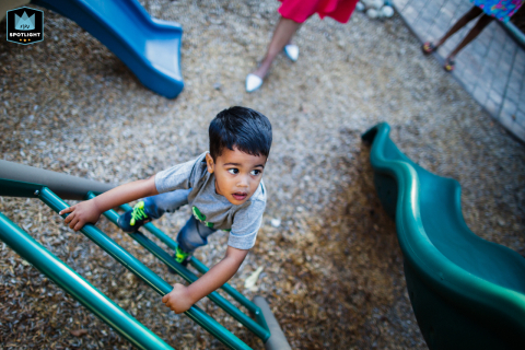 In San Francisco, California, a high-angle view captures a young boy climbing a playground ladder between two slides, showcasing his adventurous spirit and playful energy.