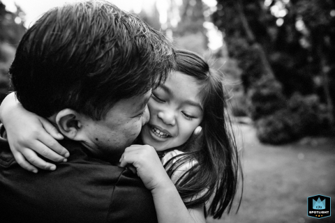 In San Francisco, California, a black-and-white close-up captures a father warmly embracing and kissing his young daughter, highlighting the tender and loving bond they share.