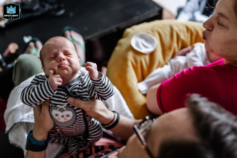 In Houston, Texas, a baby enjoys a post-feeding stretch, full of satisfaction, as mom and dad lovingly watch, sharing in this sweet, peaceful family moment.
