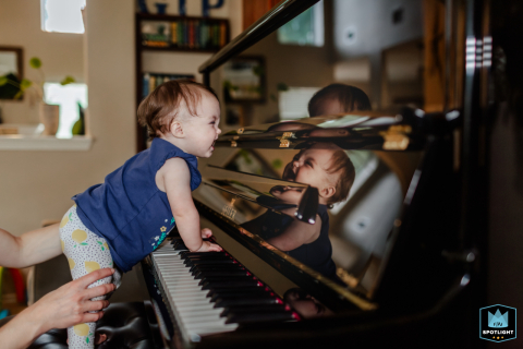 In Houston, Texas, double trouble unfolds as a baby girl is mesmerized by her reflection in the glossy black piano, her delight shining through.