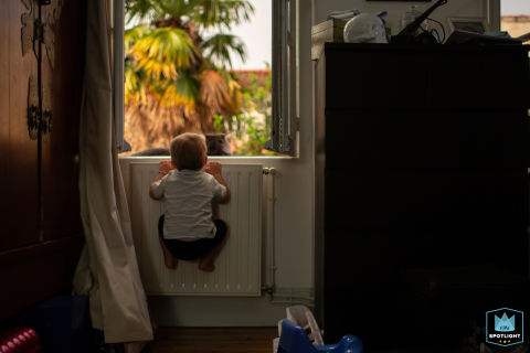 In Houston, Texas, a little boy clings to the heater, gazing out the window with his loyal cat by his side.