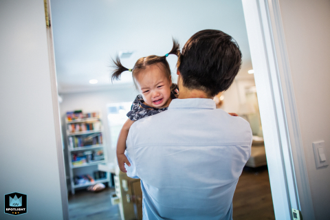 In San Francisco, California, a dad lovingly carries his toddler daughter through a doorway inside their cozy family home.