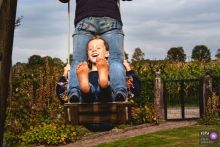 NL Familienbild-Shooting im Hinterhof des Hauses, während Sie die Schaukel mit Mama in vollen Zügen genießen