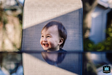In Toronto, Ontario, a toddler waits expectantly at an outdoor table, the glass surface reflecting the scene, perfectly capturing the morning anticipation of “Where’s my breakfast?”