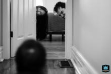 In Toronto, Ontario, a black-and-white shot captures mom and dad’s heads peeking through a doorway, playfully searching for their toddler during hide and seek.