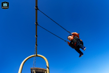 In Toronto, Ontario, a toddler boy soars joyfully on a swing beneath a dramatic blue sky, capturing the pure exhilaration and wonder of childhood play.