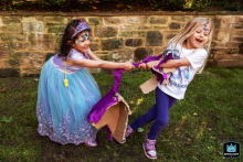 In North Yorkshire, England, children in party dresses with face paint enjoy playful moments on the grass outside during a lively and joyful birthday celebration.