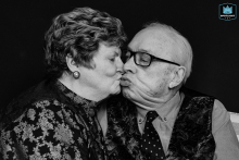 In North Yorkshire, England, an elderly couple shares a tender kiss in a tight black-and-white shot, capturing timeless love and intimacy in a single frame.