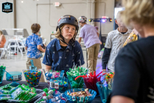 In Ventura, California, a young boy wearing a skateboard helmet looks upward, visibly distraught after being told he can’t eat the party candy yet—childhood patience tested.