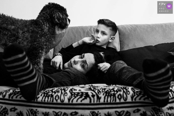 Photo by: <a href="https://www.fpja.com/documentary-family-photography-contests/joshua-dhondt/antwerpen/2060391">Joshua Dhondt - Belgium</a> A mother lays on her son's lap as she pets the family dog in this family picture by an Antwerpen photographer.