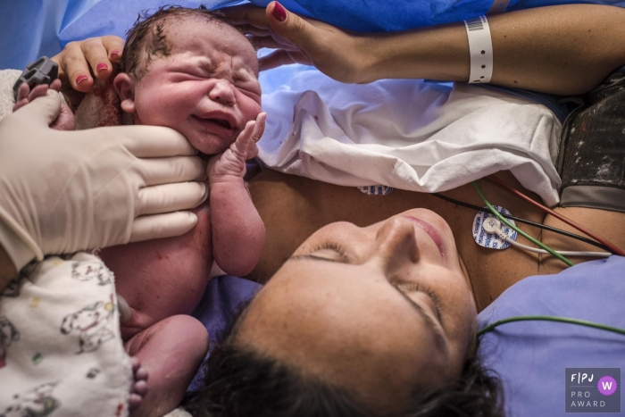Photo by: <a href="https://www.fpja.com/documentary-family-photography-contests/clara-sampaio/rio-de-janeiro/2060536">Clara Sampaio - Brazil</a> A nurse hands a newborn to its mother to hold for the first time after giving birth in the hospital in this image captured by an award-winning Rio de Janeiro, Brazil birth photographer.