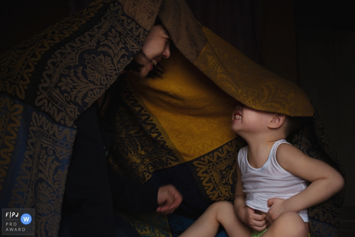 Photo by: <a href="https://www.fpja.com/documentary-family-photography-contests/moana-wu/shanghai/2061541">Moana Wu - China</a> A mother plays with her baby under a blanket in this award-winning photo by a Shanghai, China family photographer.