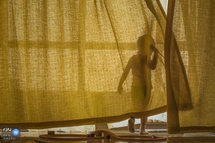 La silhouette d’un petit garçon est visible à travers un rideau sur cette image créée par un photographe de famille de Shanghai, Chine.