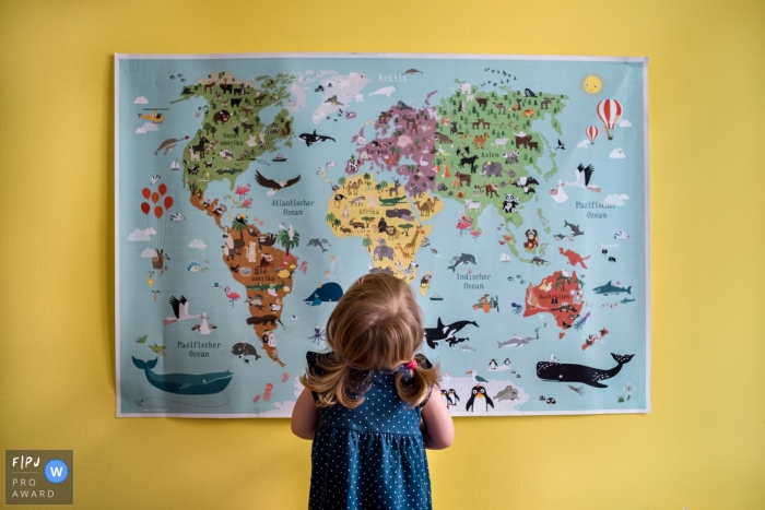 A little girl stares up at a map of the world in this Family Photojournalist Association contest awarded photo created by a Berlin, Germany family photographer. 