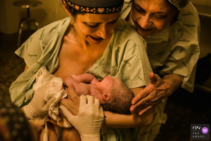 Photo by: <a href="https://www.fpja.com/documentary-family-photography-contests/adriana-costa/belo-horizonte/2062176">Adriana Costa - Brazil</a> A mother holds her newborn in the hospital as her own mother comes to see in this image composed by an award-winning Minas Gerais birth photographer.