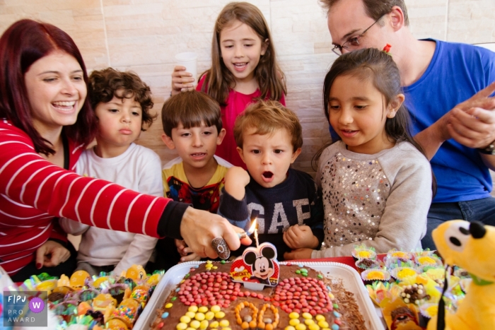 A little boy waits excitedly as his mother lights the candle on his birthday cake in this family picture by a Sao Paulo, Brazil photographer. 