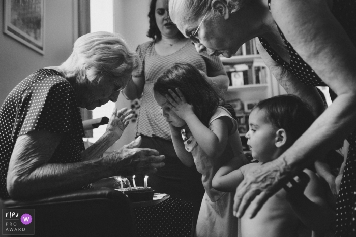 A little girl helps her grandmother blow out the candles on her birthday cake in this photograph created by a Rio de Janeiro, Brazil family photojournalist. 