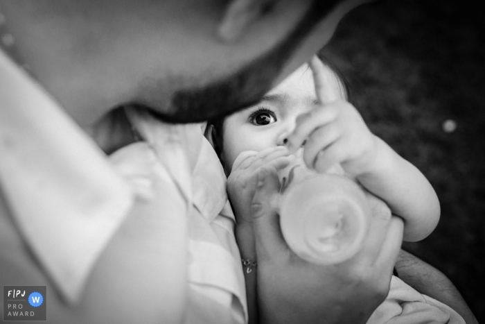 Photo by: <a href="https://www.fpja.com/documentary-family-photography-contests/gabi-marques/minas-gerais/2063396">Gabi Marques - Brazil</a> A father bottle feeds his baby in this documentary-style family image recorded by a Minas Gerais, Brazil photographer.