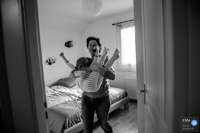 Photo by: <a href="https://www.fpja.com/documentary-family-photography-contests/nadine-court/savoie/2063926">Nadine Court - France</a> a mother tries to carry her uncooperative daughter in this family picture by a Savoie photographer.
