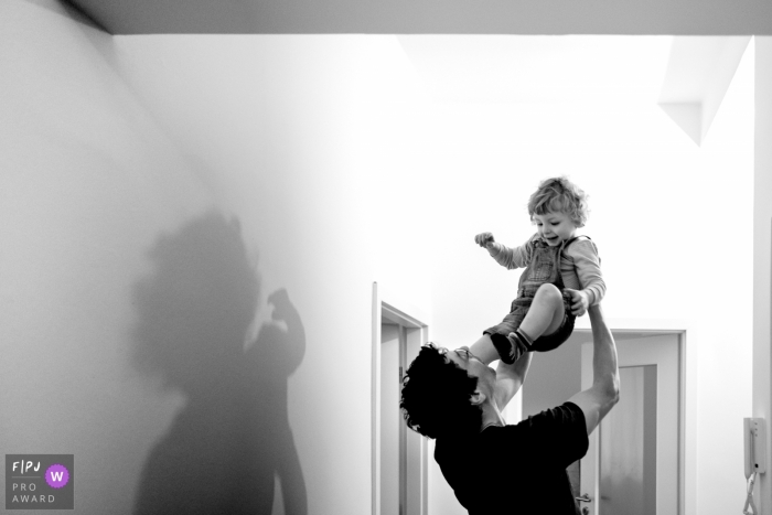 Un père élève son fils haut dans les airs dans cette image primée d'un prix FPJA par un photographe de famille de Berlin, Allemagne.