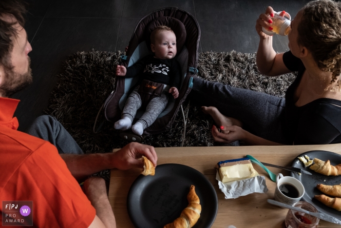 A baby watches as his mother and father eat breakfast in this FPJA award-winning picture by a Gelderland, Netherlands family photographer.