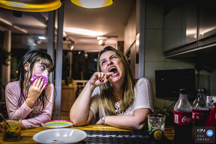 Photo by: <a href="https://www.fpja.com/documentary-family-photography-contests/gab-campello/s%C3%A3o-paulo/2065991">Gab Campello - Brazil</a> A girl looks at her mother as she picks her teeth in this Family Photojournalist Association awarded photo by a Sao Paulo, Brazil documentary family photographer.