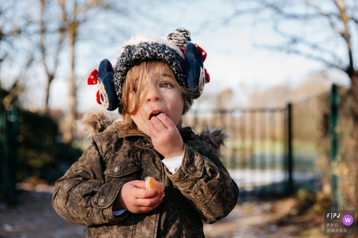 Photo by: <a href="https://www.fpja.com/documentary-family-photography-contests/estelle-chhor/h%C3%A9rault/2066056">Estelle Chhor - France</a> A little boy eats an orange outside in this photograph created by a Herault family photojournalist.