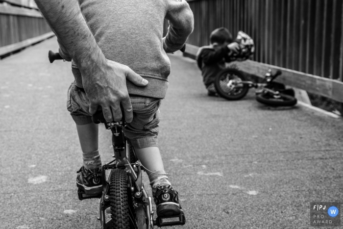 Un père enseigne à son fils comment faire du vélo dans cette image de famille de style documentaire enregistrée par un photographe écossais.