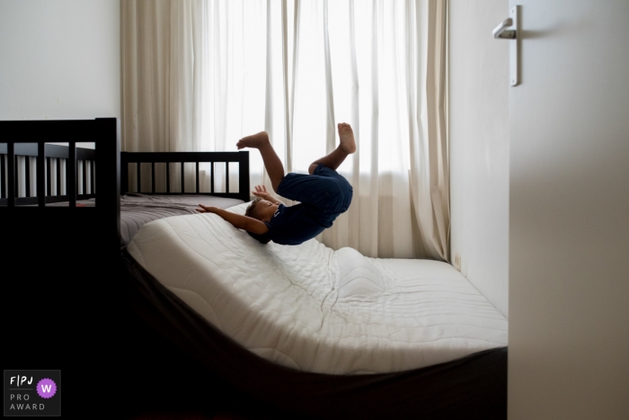 Photo by: <a href="https://www.fpja.com/documentary-family-photography-contests/gonda-meurs/noord-holland/2066201">Gonda Meurs - Netherlands</a> A boy jumps onto a mattress on the floor in this FPJA award-winning picture by a Netherlands family photographer.