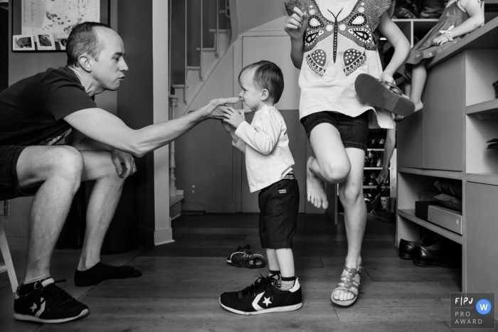 A little boy tries on his father's shoe as the family gets ready to go outside in this picture captured by a Paris, France family photojournalist. 