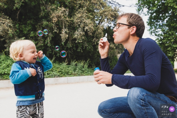 Photo by: <a href="https://www.fpja.com/documentary-family-photography-contests/annie-gozard/paris/2066756">Annie Gozard - France</a> A father blows bubbles for his son in this photo by a Paris, France award-winning family photographer.