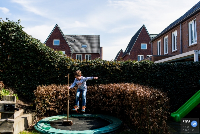 A boy jumps on a trampoline while holding a broom in this award-winning photo by a Modena family photographer.