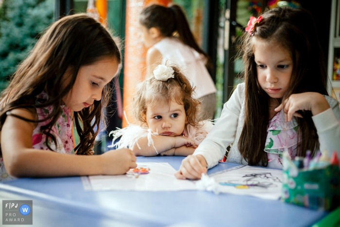 Two girls color while their younger sister watches in this picture captured by an Armenia family photojournalist. 