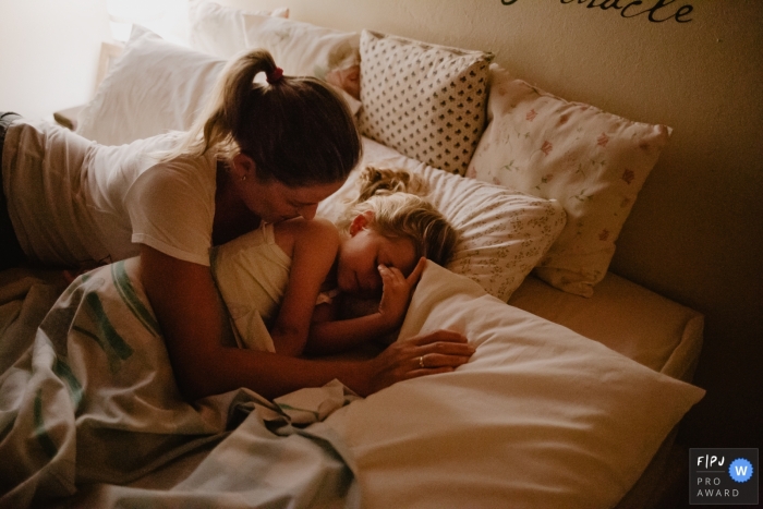 Photo by: <a href="https://www.fpja.com/documentary-family-photography-contests/thiago-braga/florianopolis/2068231">Thiago Braga - Brazil</a> A mother tries to wake up her sleeping daughter in this image created by a Florianopolis family photographer.
