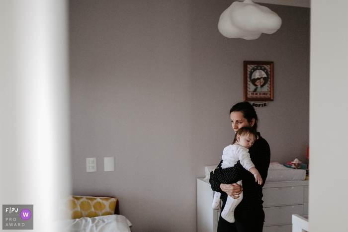 A mother carries her sleeping baby in this photo by a Florianopolis award-winning family photographer. 