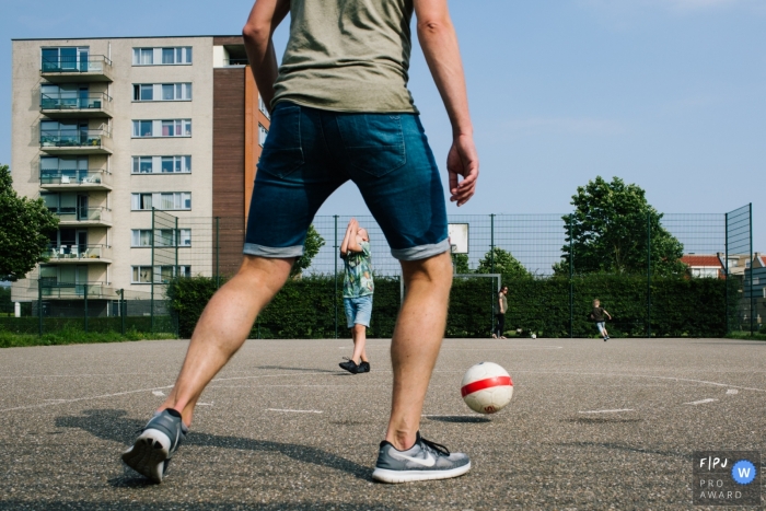 Un père et son fils jouent à l’extérieur sur un terrain de basketball avec cette image de famille de style documentaire enregistrée par un photographe néerlandais.