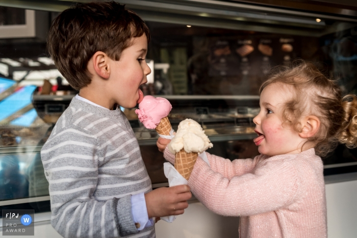 Photo by: <a href="https://www.fpja.com/documentary-family-photography-contests/sybil-rondeau/nantes/2068501">Sybil Rondeau - France</a> A little girl feeds her bother an ice cream cone in this image created by a Nantes family photographer.
