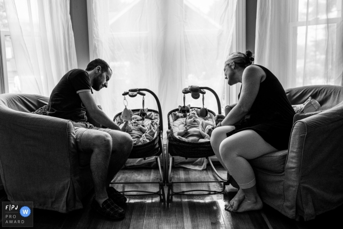 A mother and father watch their two babies in the living room in this photo by a Boston, MA award-winning family photographer. 